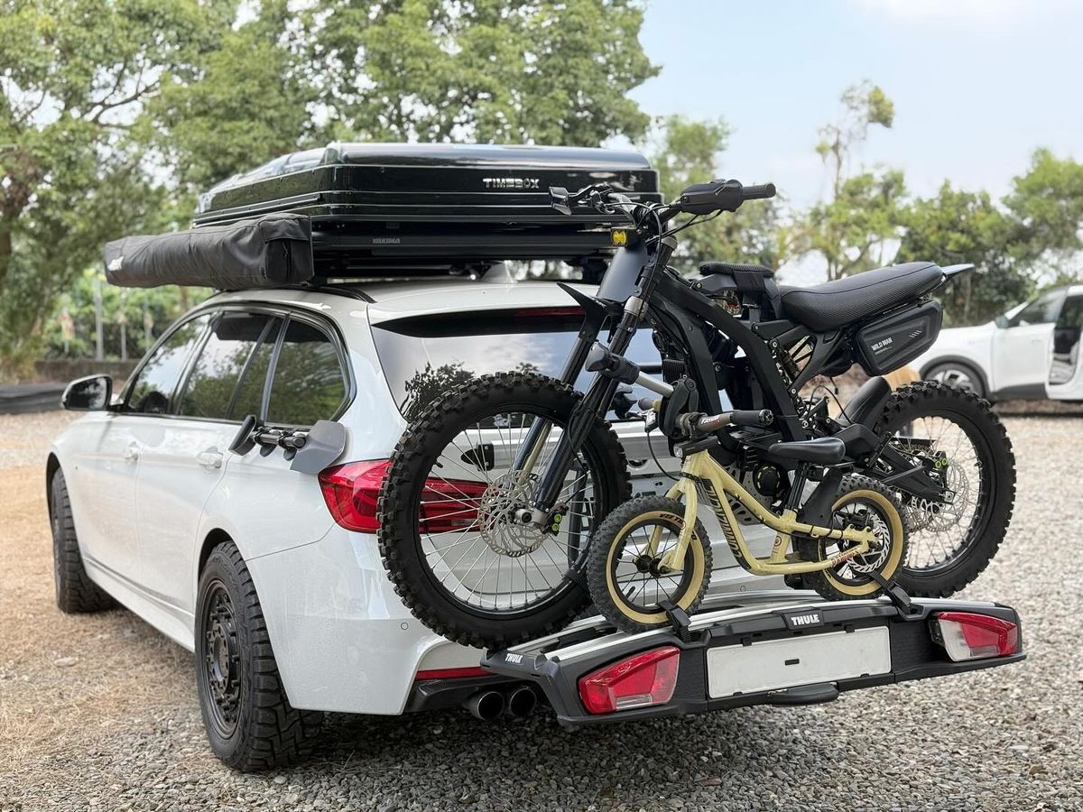 Thule hitch bike rack carrying two electric dirt bikes on a white BMW F31 wagon