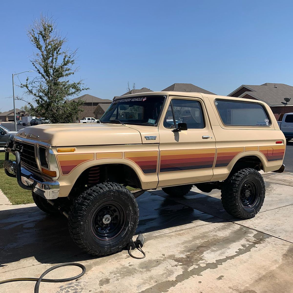 1978 Ford Bronco Full-Size in tan with retro sunset stripe graphics parked in a driveway