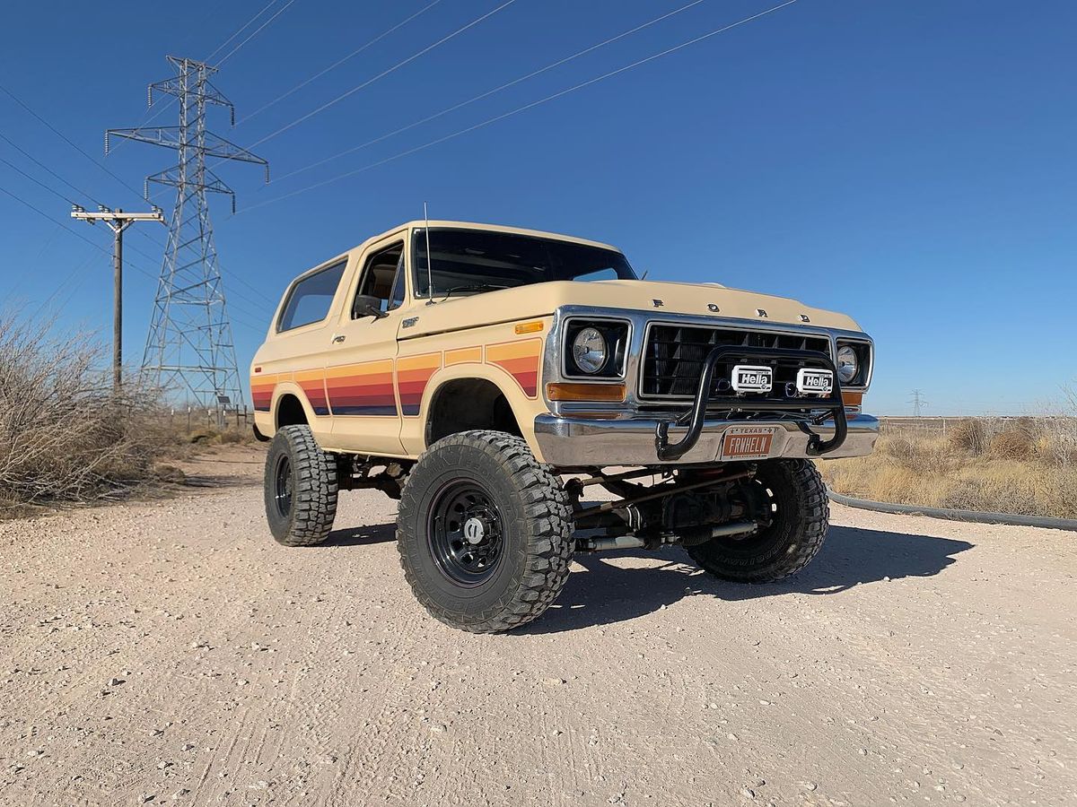 Ford Super Duty axle swap visible under a lifted tan 1978 Ford Bronco on a dirt road