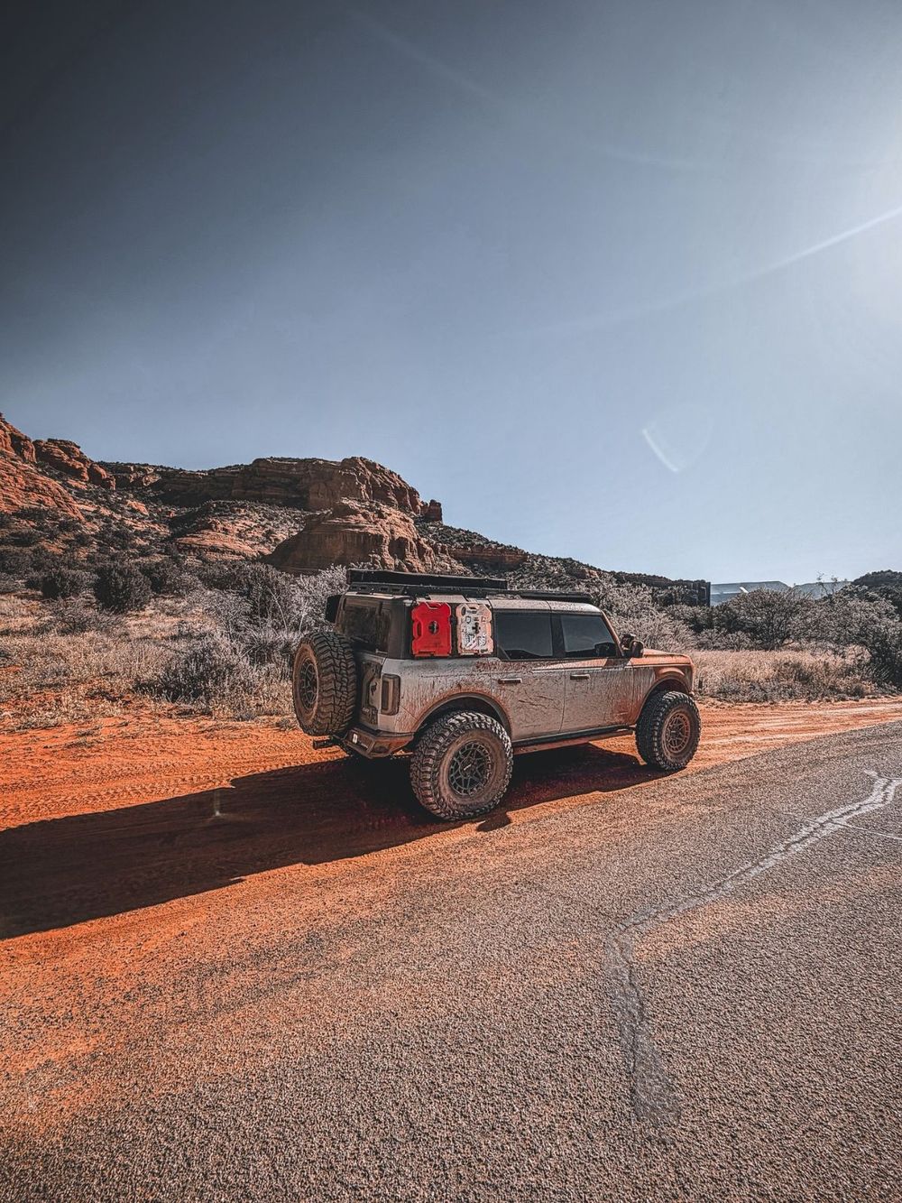 Lifted Ford Bronco Wildtrak with oversized mud-terrain tires on red dirt road in Sedona
