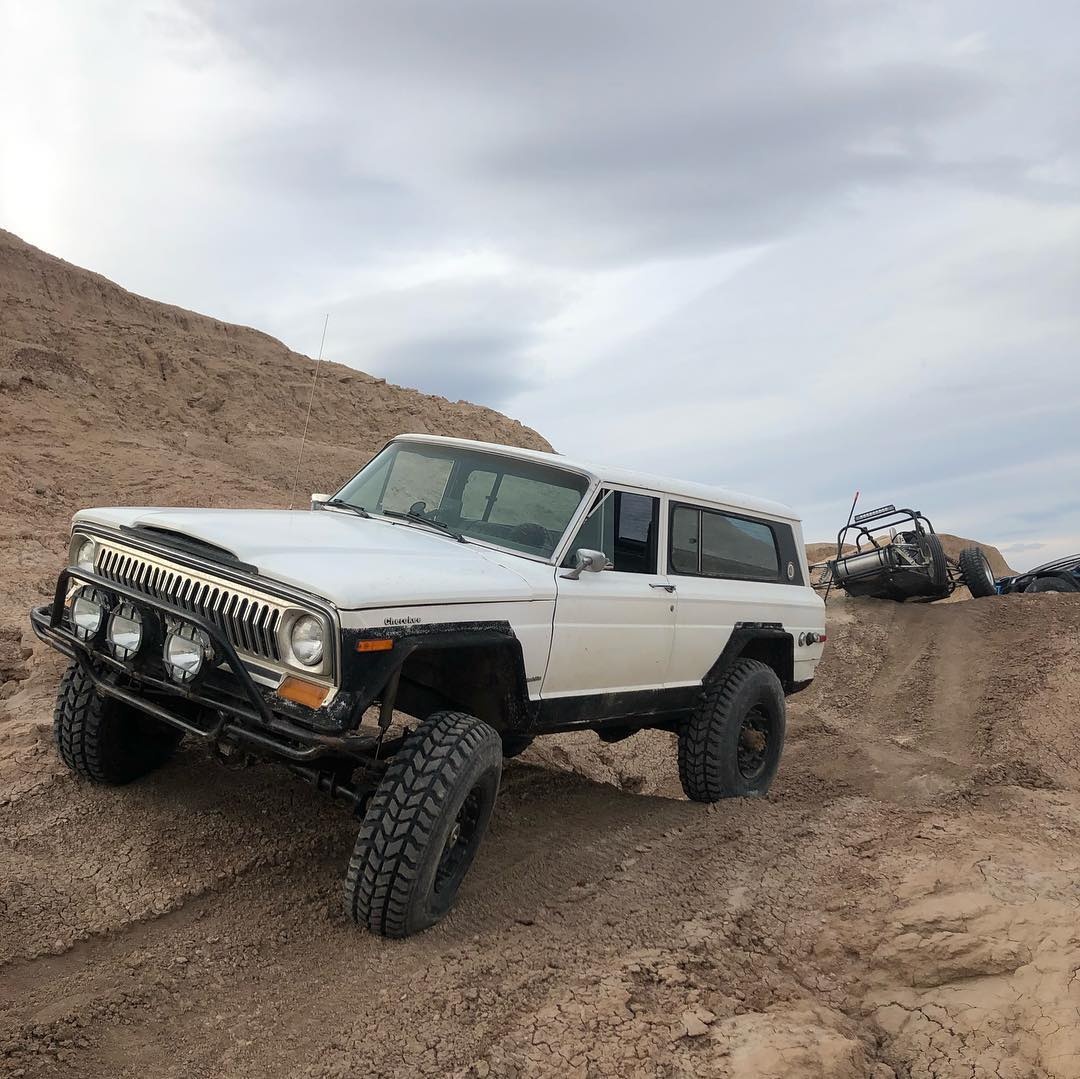 White 1978 Jeep Cherokee Chief SJ on Deaver springs navigating muddy rutted terrain
