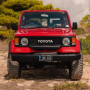 Red Toyota Land Cruiser 70 with black grille and round headlights