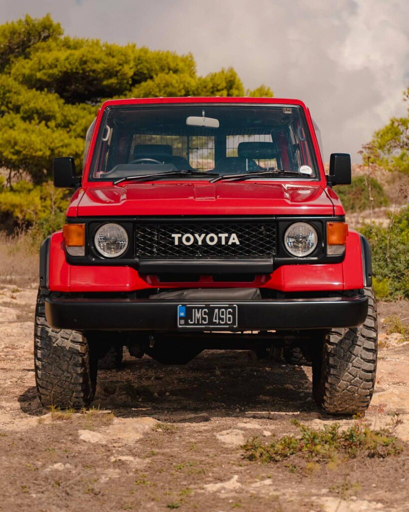 Red Toyota Land Cruiser 70 with black grille and round headlights