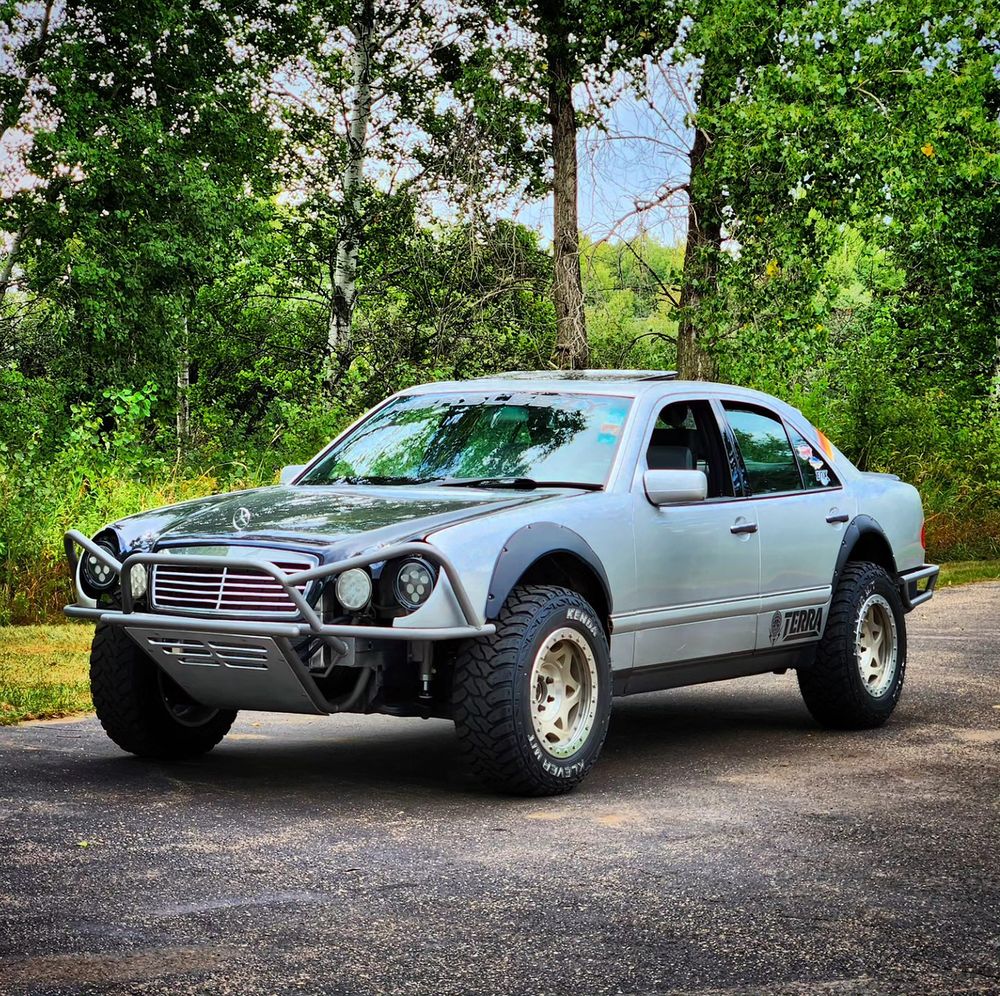 1998 Mercedes W210 E430 silver prerunner with fender flares and tube bumper in a driveway