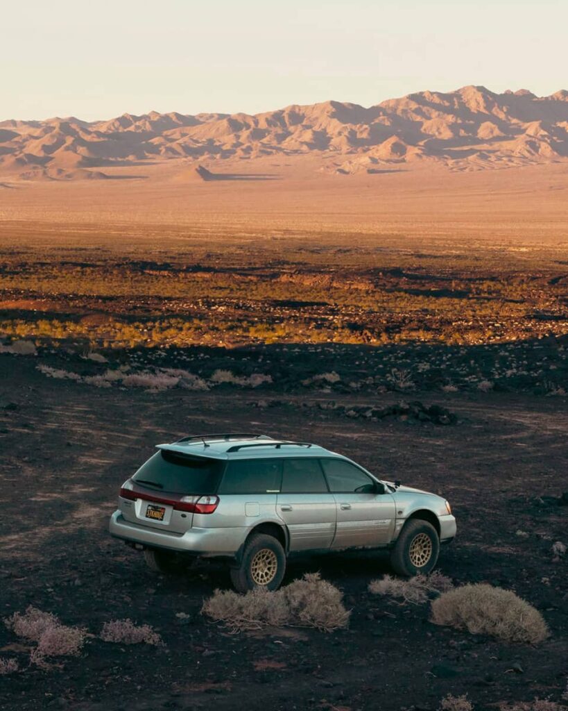 Silver Subaru Outback off-roading in the wild terrain and mountains in USA