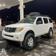 White Nissan Pathfinder with a titan suspension and 35 inch tires