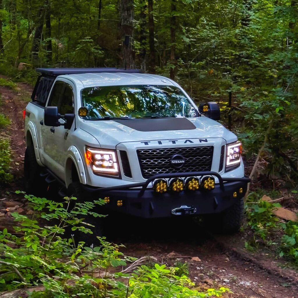 Lifted Nissan Titan with Custom Morimoto XB LED lights off-roading in the forest trails