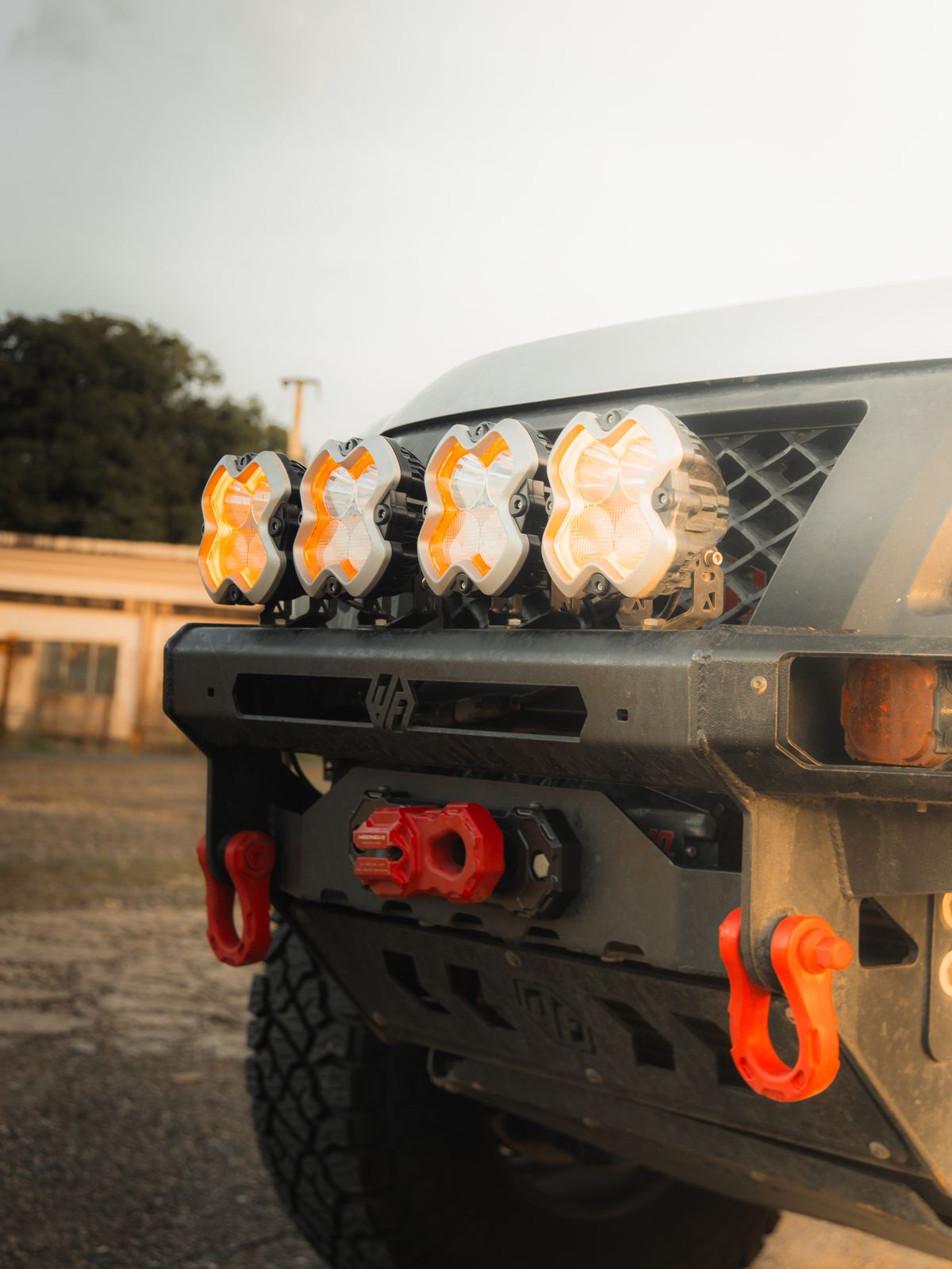 Four Baja Designs X-Link amber pod lights mounted on the front bumper of a Nissan Xterra