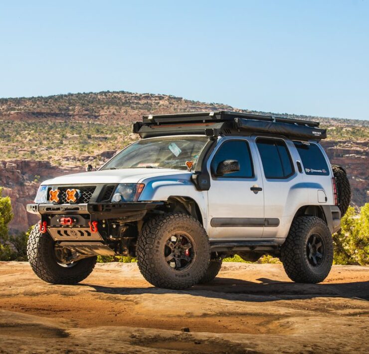 Silver 2005–2015 Nissan Xterra Titan Swap build posed on desert rock under clear blue sky