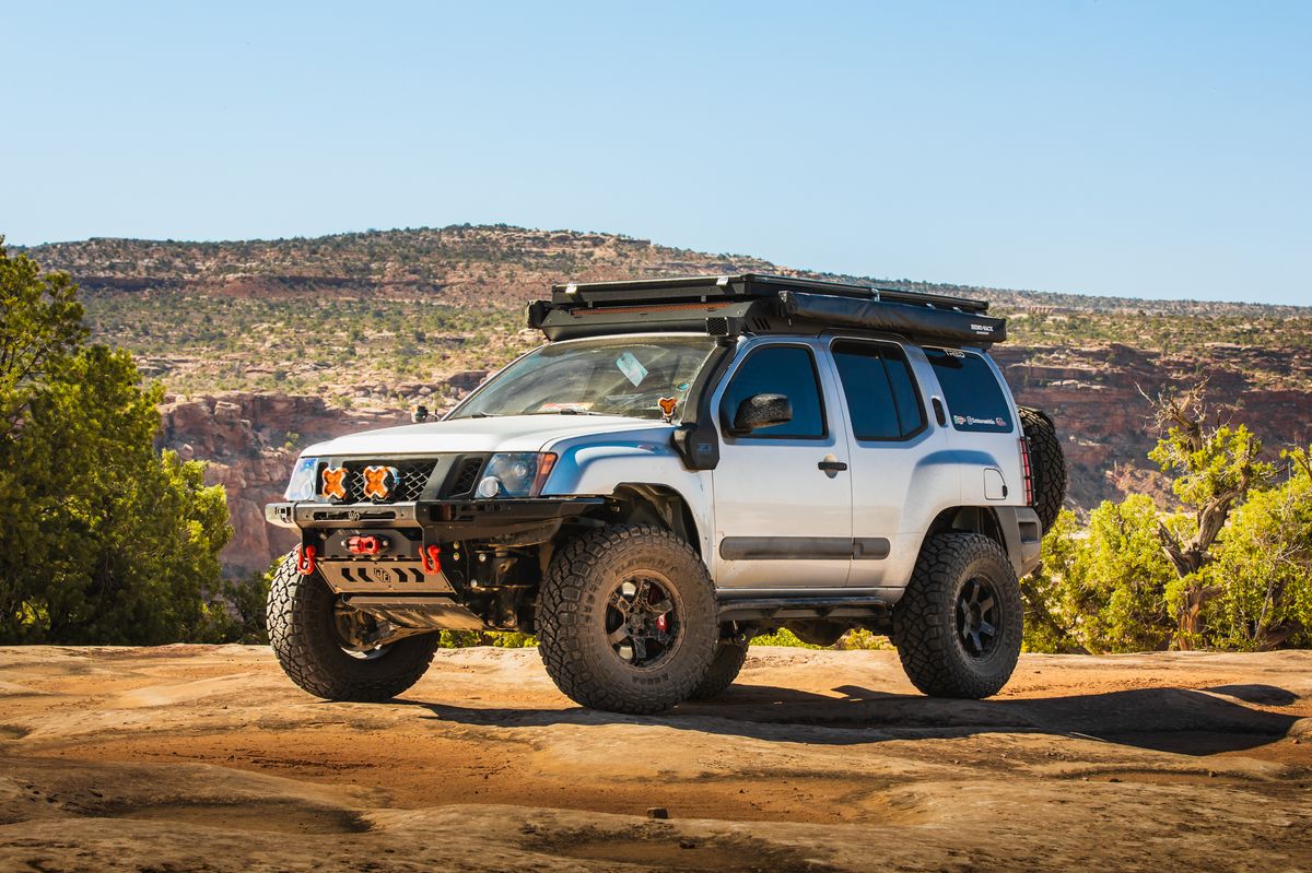 Silver 2005–2015 Nissan Xterra Titan Swap build posed on desert rock under clear blue sky