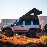 Nissan Xterra with rooftop tent fully deployed while camping on Moab red rock at dusk