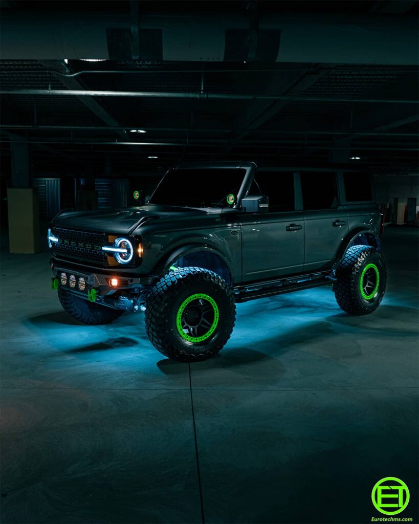 Lifted Ford Bronco with blue rock lights in the wheel well that allow seeing what's under it