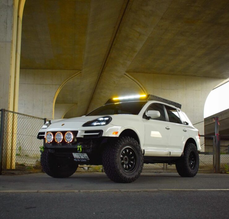 White 957 Porsche Cayenne with STEDI off-road lights on a custom front bumper under a bridge