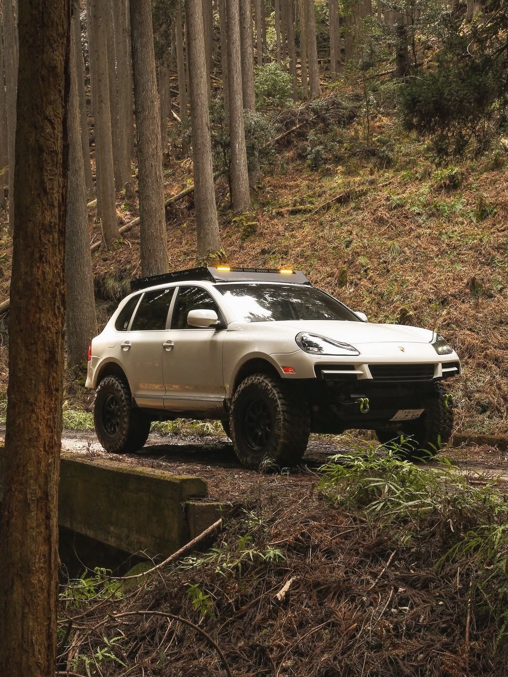 White Porsche Cayenne 957 with AP Original 3-inch lift navigating a muddy forest trail