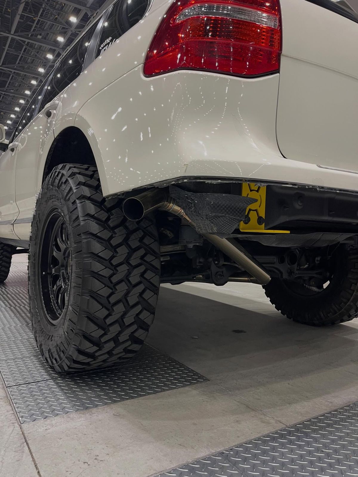 Custom exhaust tip exit visible beneath the rear bumper of the lifted Porsche Cayenne