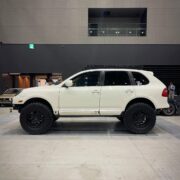 Side profile of white lifted Porsche Cayenne showing roof rack and 35x12.50R18 tires