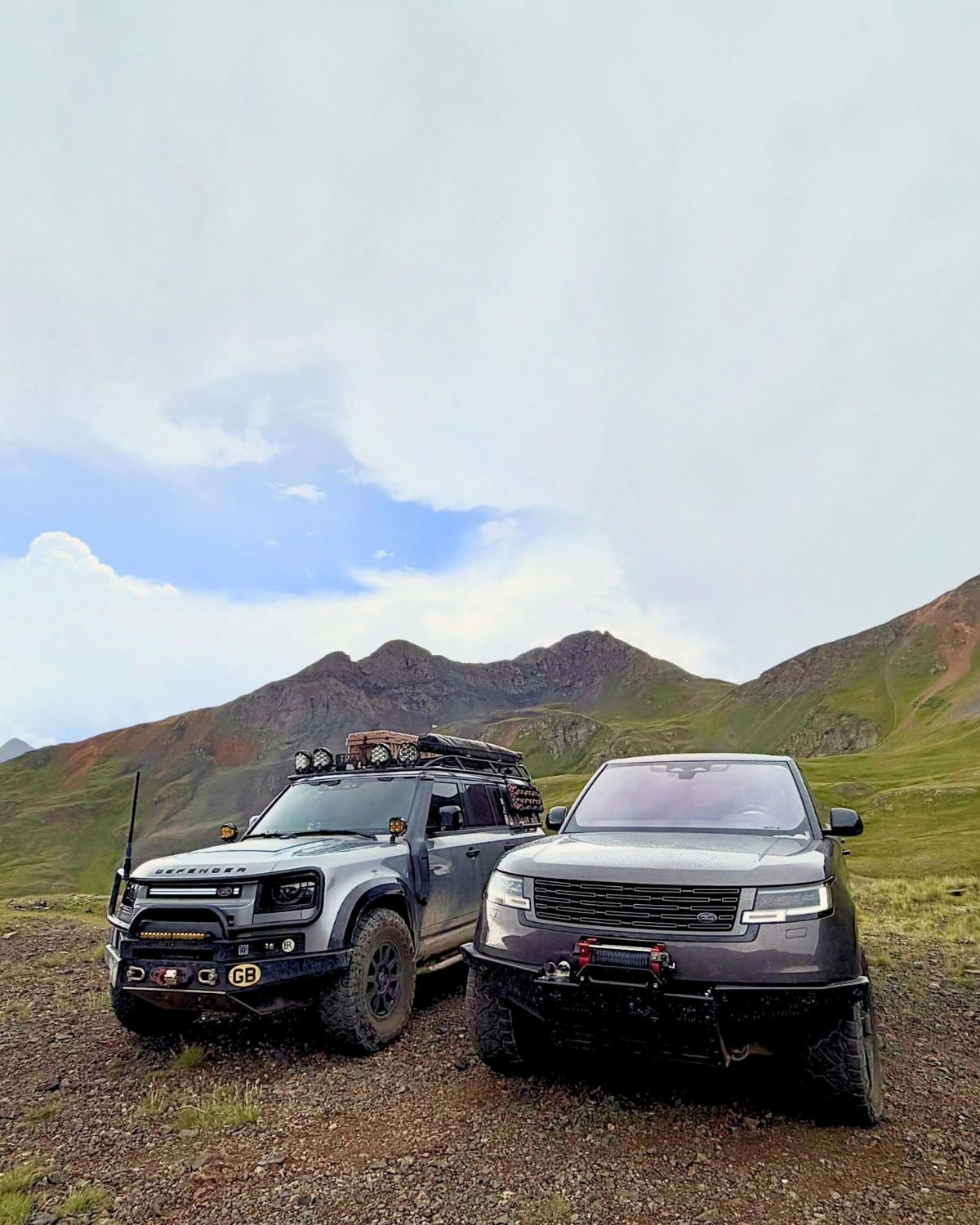 Range Rover L460 beside a Land Rover Defender on a high-altitude dirt trail