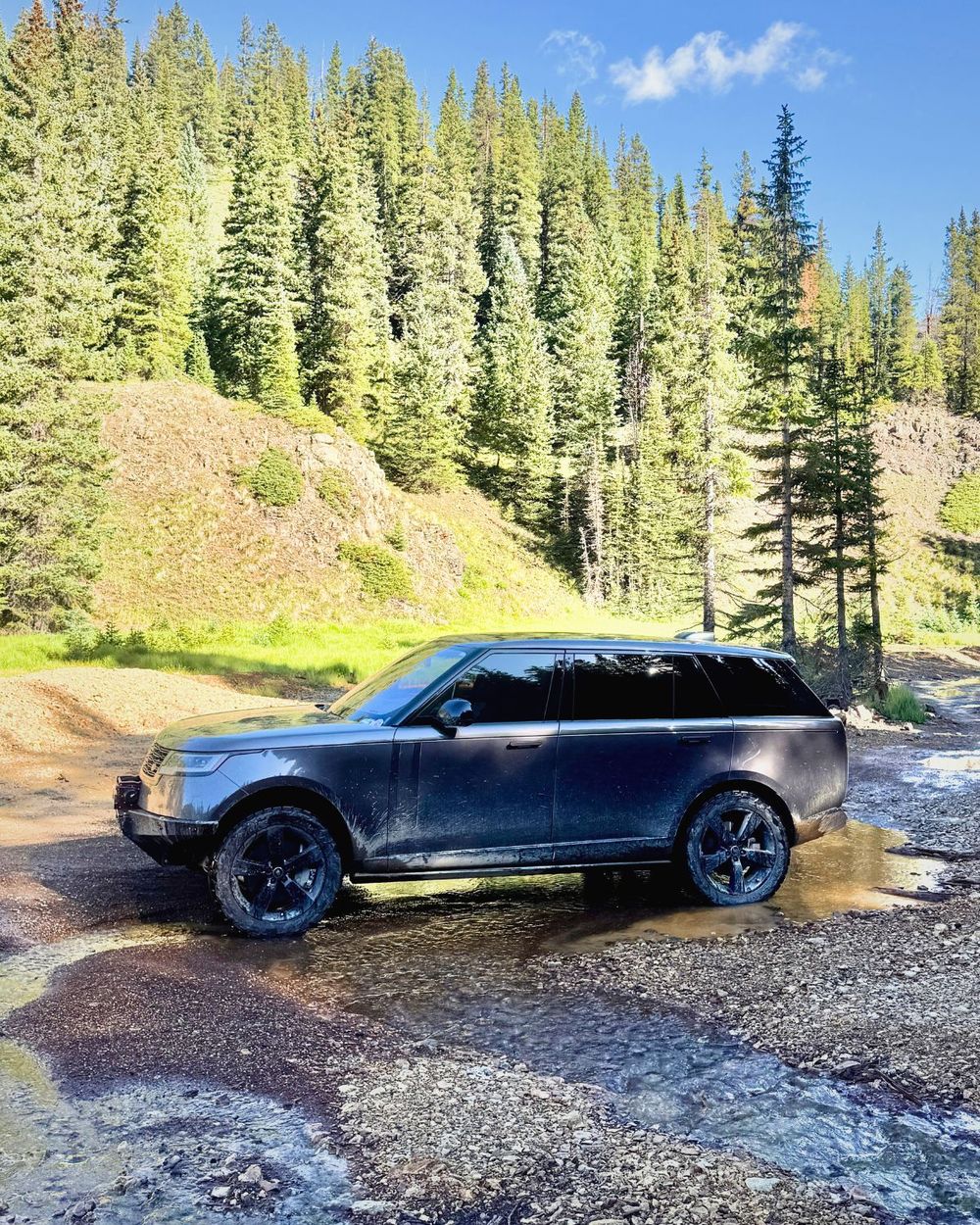 Sarek Autowerke aluminum rock sliders on a Range Rover L460 crossing a muddy stream
