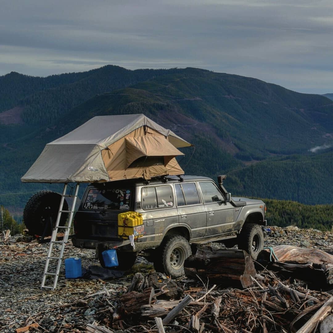 ARB rooftop tent fully deployed on a 1981 Toyota Land Cruiser BJ60 in dark grey at a mountain campsite