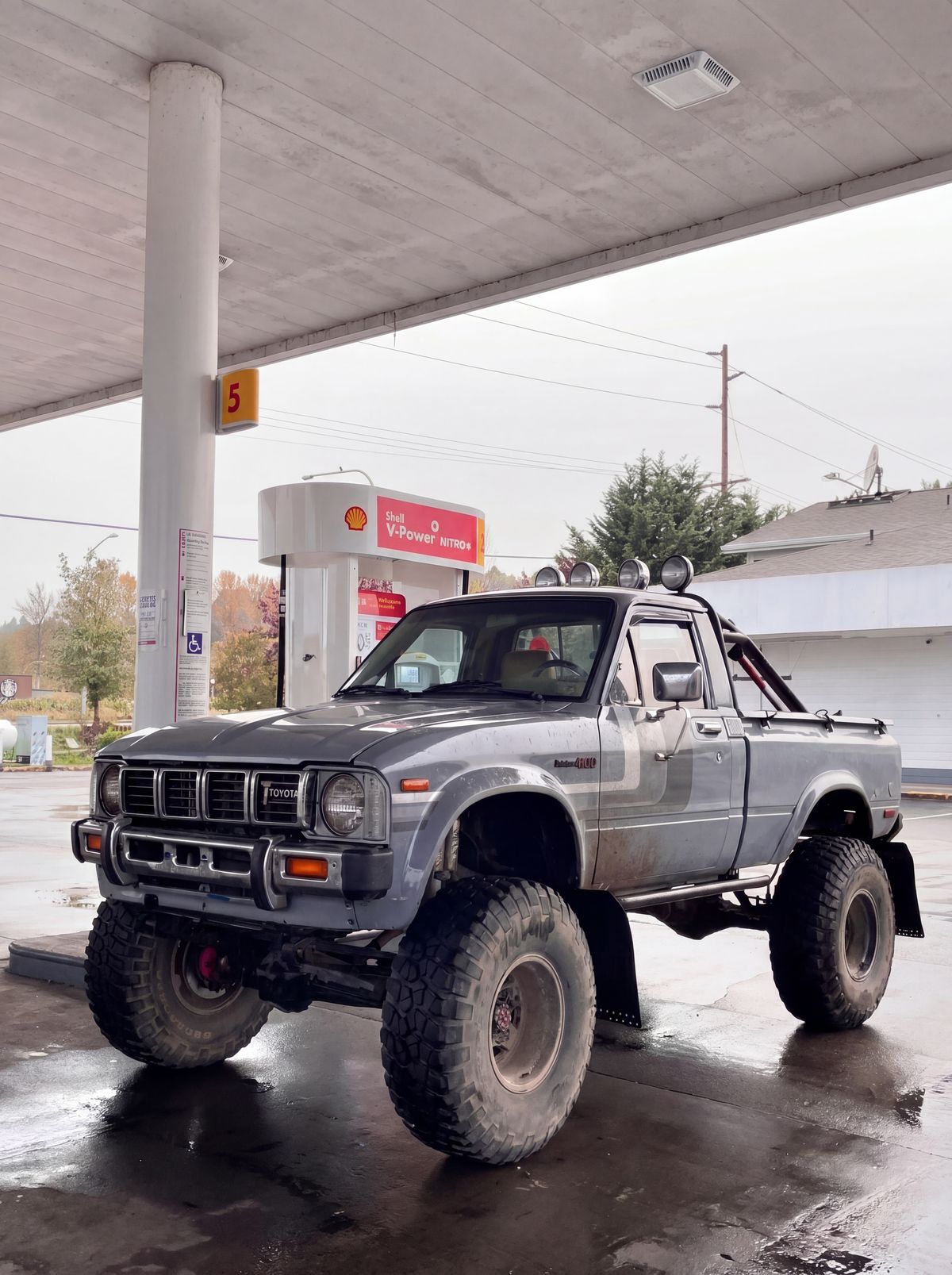 35-inch BFG KM3 mud-terrain tires on a lifted gray Toyota Pickup at a Shell gas station