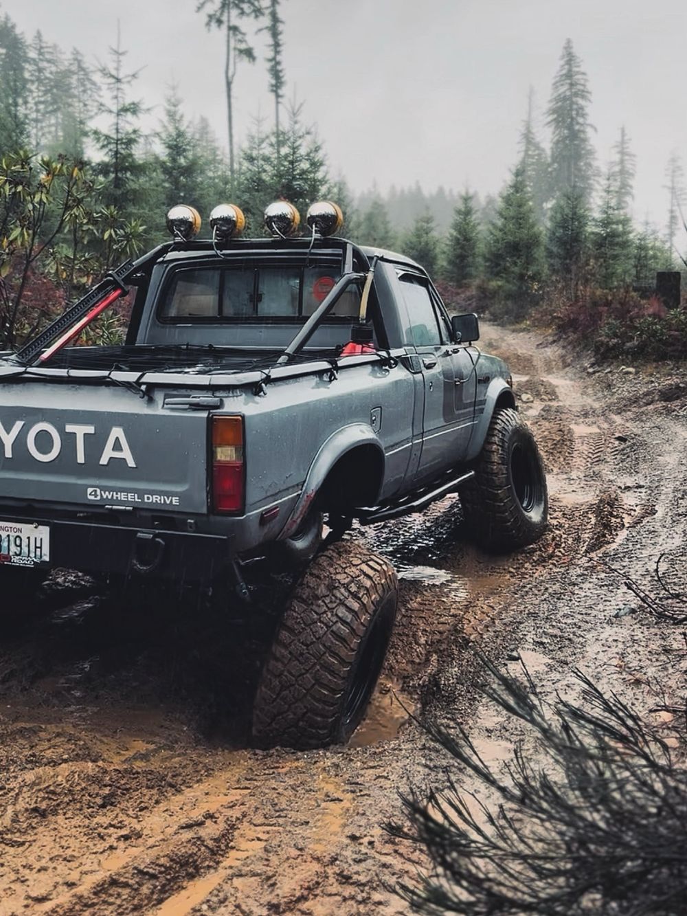 Gray Toyota Pickup 4x4 rear view showing Detroit Locker axle churning through deep mud trail