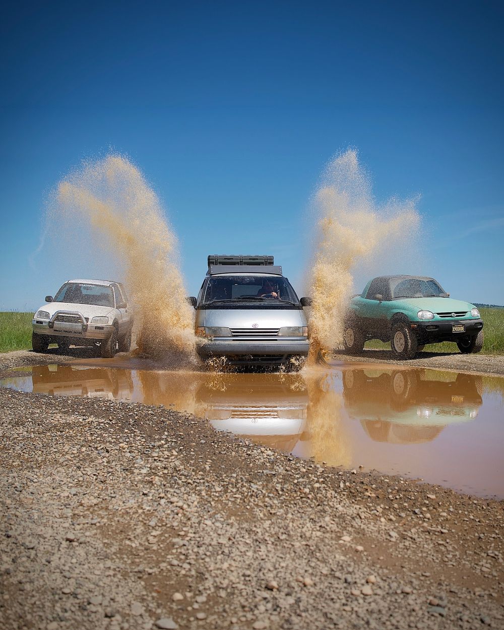 1994 Toyota Previa Alltrac in silver splashing through a muddy puddle with General Grabber A/Tx tires