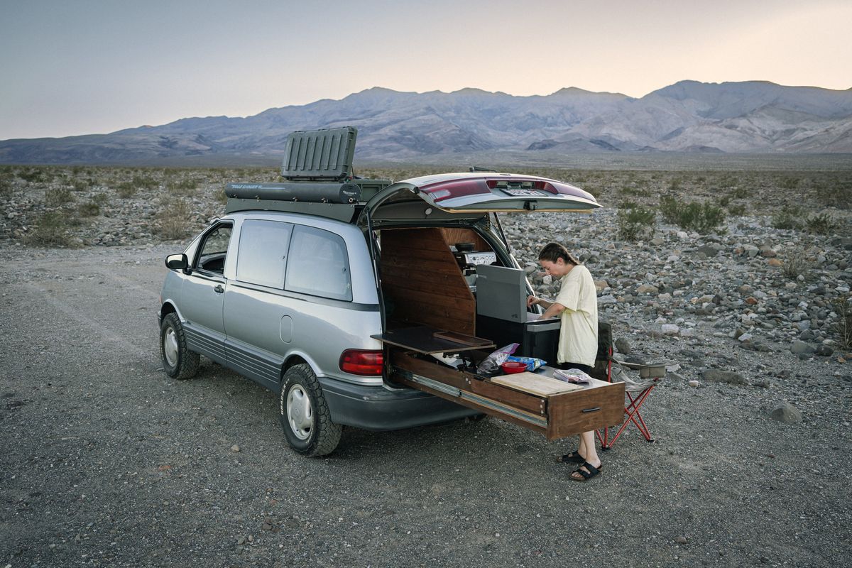 95L Roam box on the roof rack of a Toyota Previa overland van parked in a desert landscape