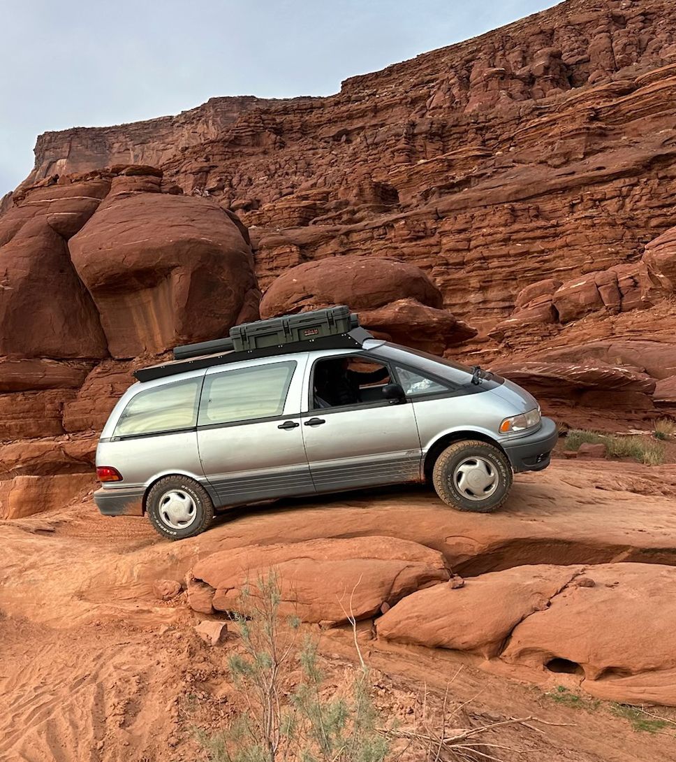 Toyota Previa overland van navigating red rock terrain in Moab with a 2-inch suspension lift