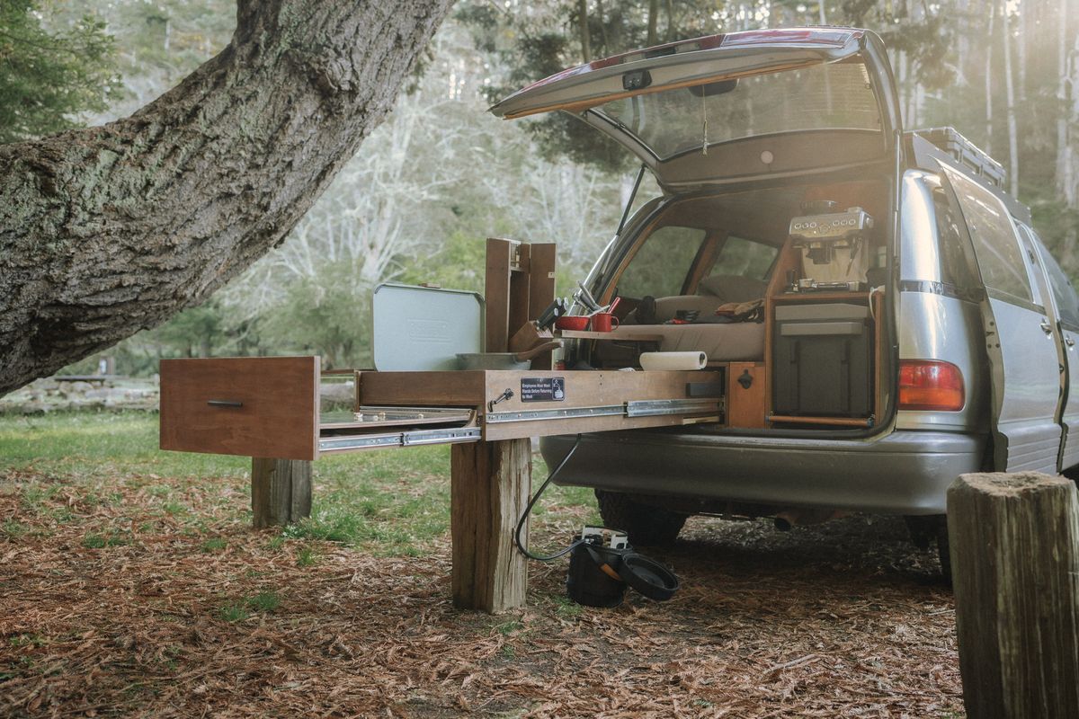 Full-size pull-out kitchen drawer system extended from a Toyota Previa camper van in a forest