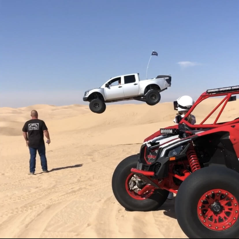 Long travel Nissan Titan Prerunner sending it jumping the dunes